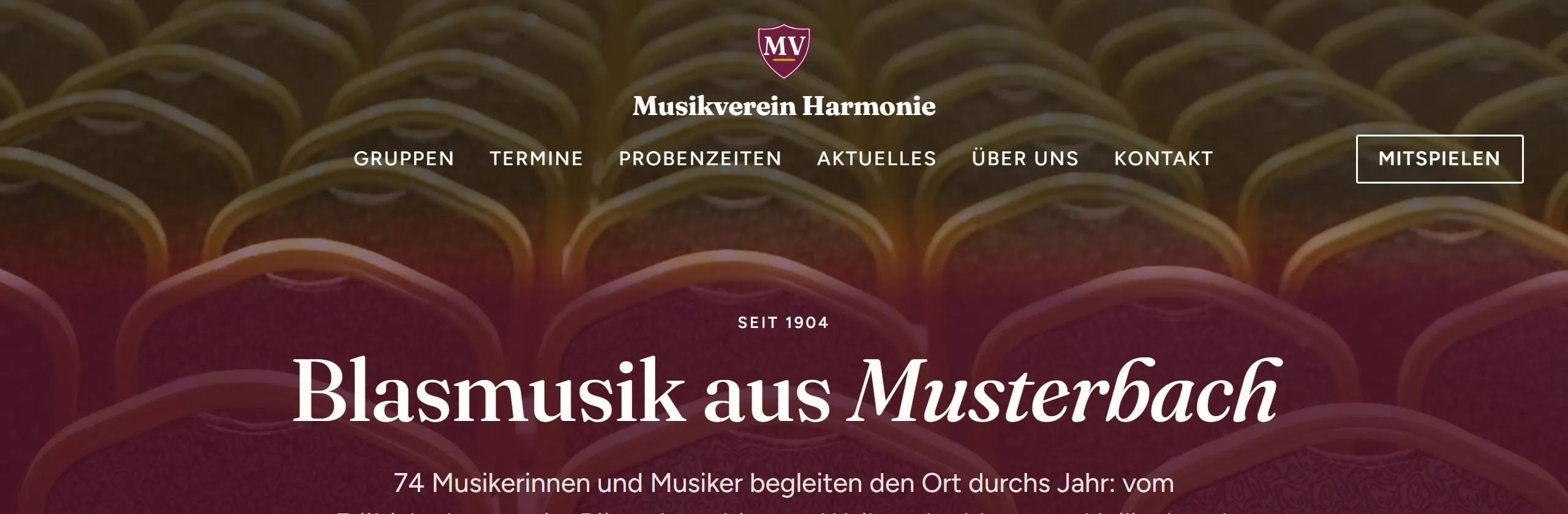 Der Kopf „Logo in der Mitte“ beim Demoverein „Musikverein Harmonie“: Wappen und Name stehen in der Mitte, darunter in einer eigenen Zeile das Menü in Versalien (Gruppen, Termine, Probenzeiten, Aktuelles, Über uns, Kontakt), am rechten Ende der Zeile der Hauptknopf „Mitspielen“. Der Kopf hat keinen eigenen Hintergrund, er liegt auf dem großen Bild am Seitenanfang.